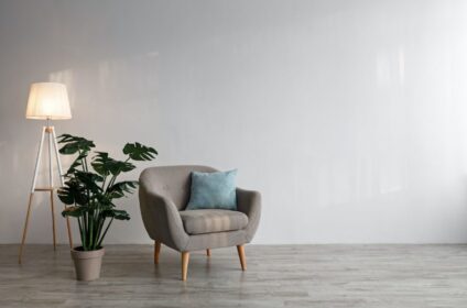 Cozy armchair with pillow luminous lamp large green plant in pot on floor on gray wall background